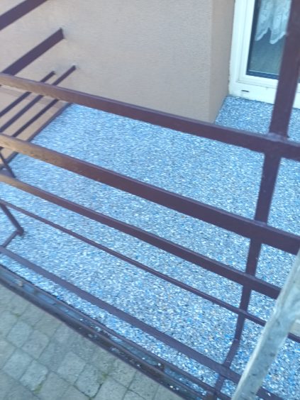 Posadzka z płatkami widoczna przez balustradę balkonu